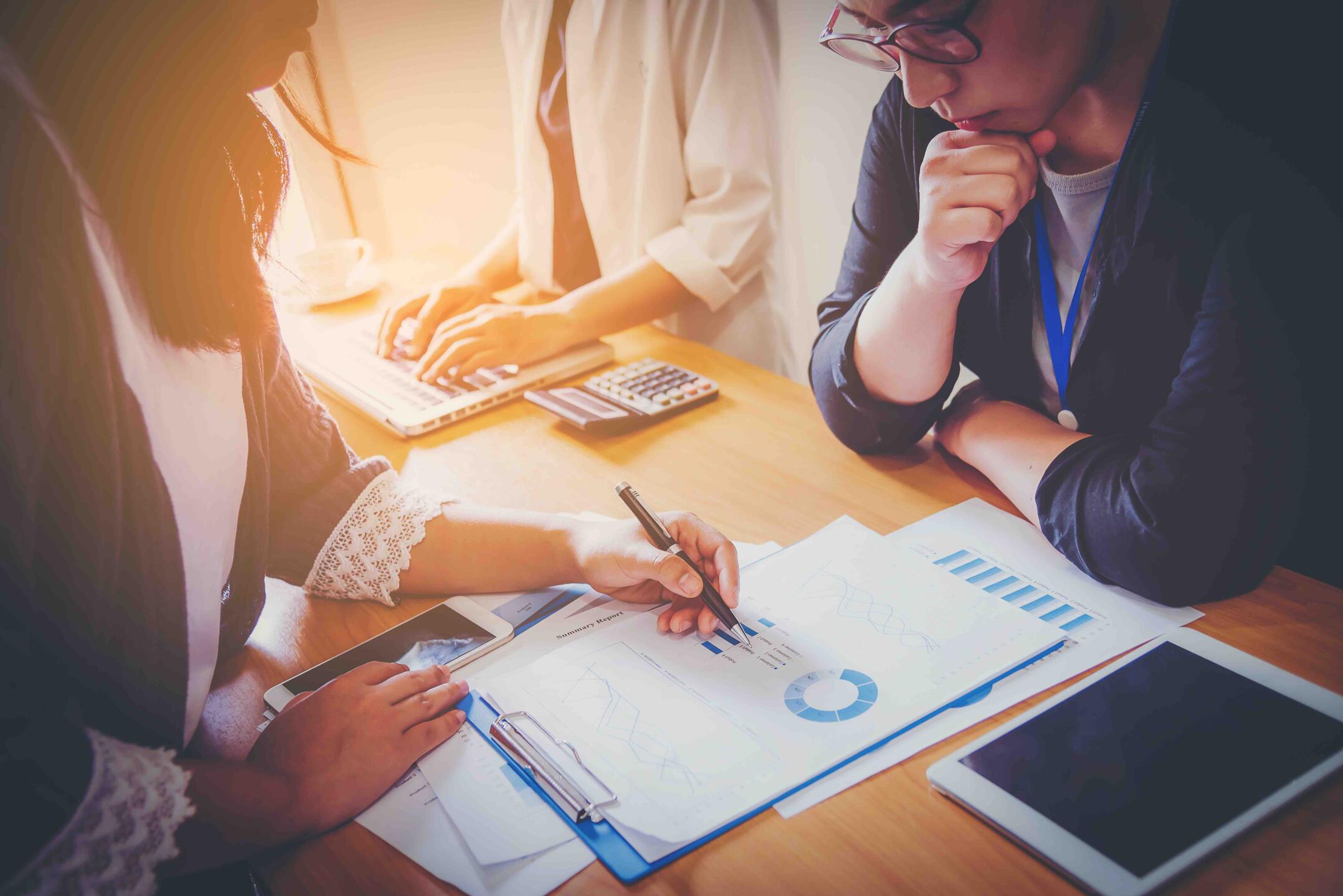 Business meeting, man's hands pointing on charts. Reflection light and flare. Concept image of data gathering and statistical working.