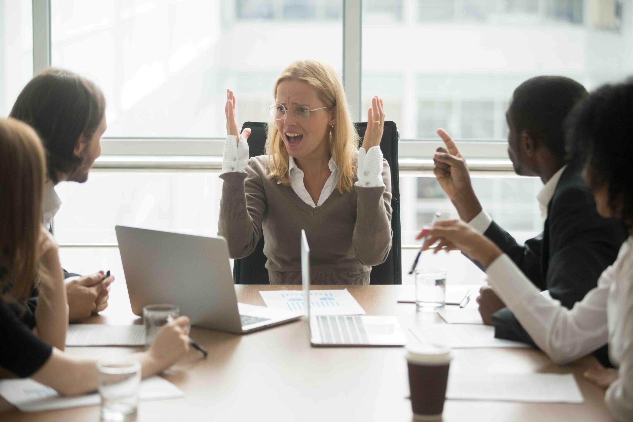 Stressed angry businesswoman arguing at meeting with diverse male colleagues, woman boss team leader confused about bad attitude and bullying, suffering from disrespect, gender discrimination at work